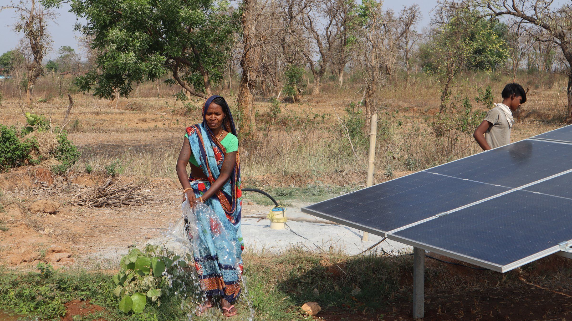 A woman farmer next to solar panels used for irrigation